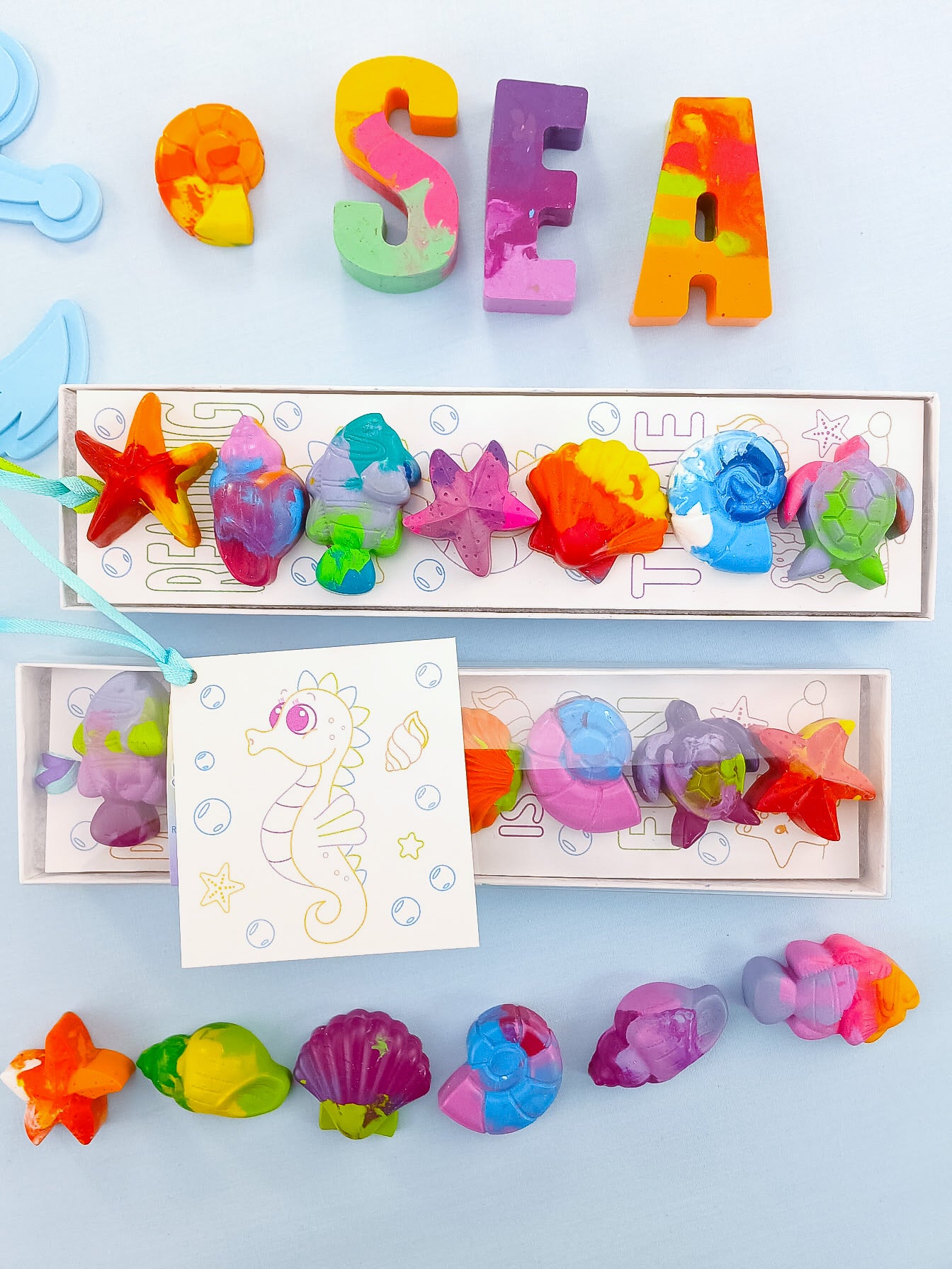 Six sea creature crayons in gift box with colorful shells, turtles, and starfish, perfect for ocean party favors.