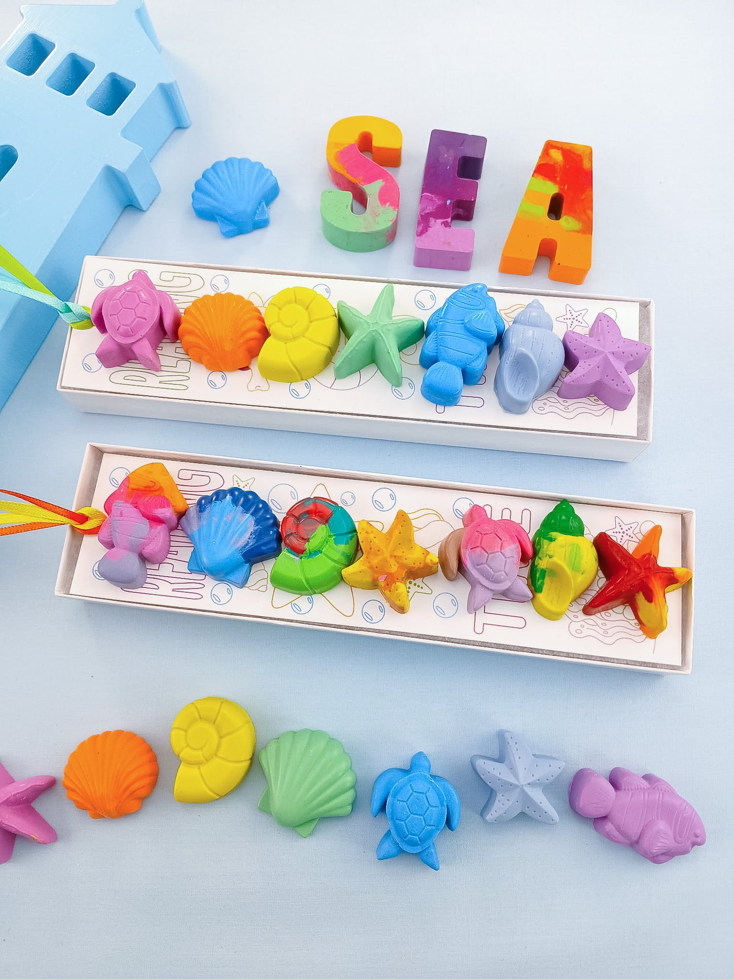 Two gift boxes of handmade sea creature crayons with turtles, shells, and starfish in rainbow and pastel colors, non-toxic and ready for kids’ party favors or classroom gifts.