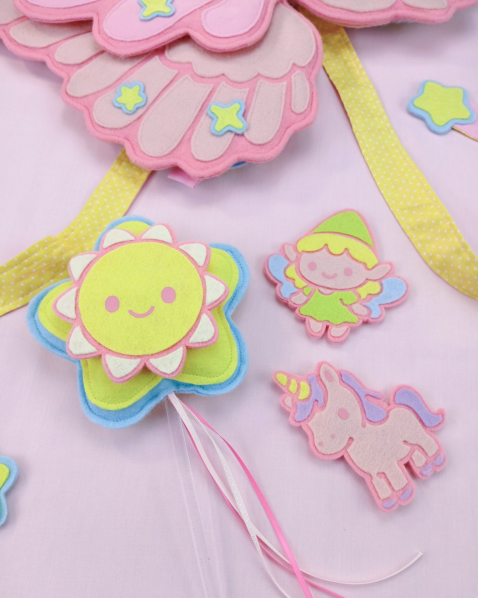 Wand with snap-on sun, unicorn and fairy charms displayed alongside felt Pegasus wings, Rainbows & Dreams exclusive.