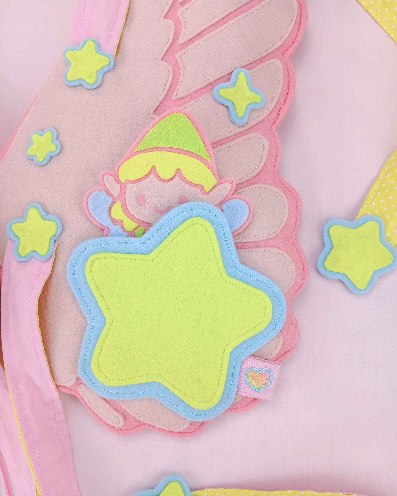 Close-up of bespoke pink felt fairy wings charm pocket of pastel stars and fairy charm, heirloom Rainbows & Dreams design.