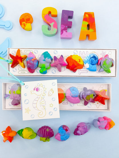 Six sea creature crayons in gift box with colorful shells, turtles, and starfish, perfect for ocean party favors.
