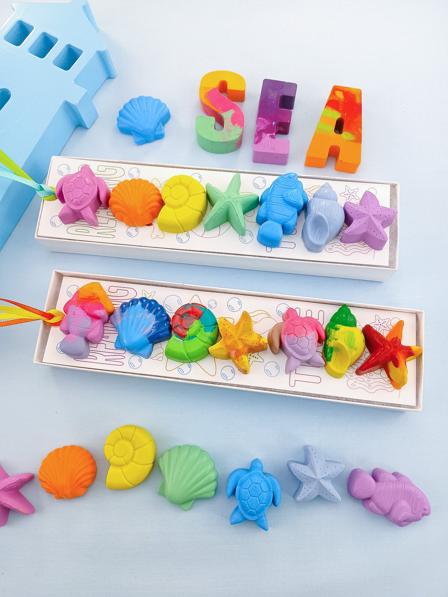 Two gift boxes of handmade sea creature crayons with turtles, shells, and starfish in rainbow and pastel colors, non-toxic and ready for kids’ party favors or classroom gifts.